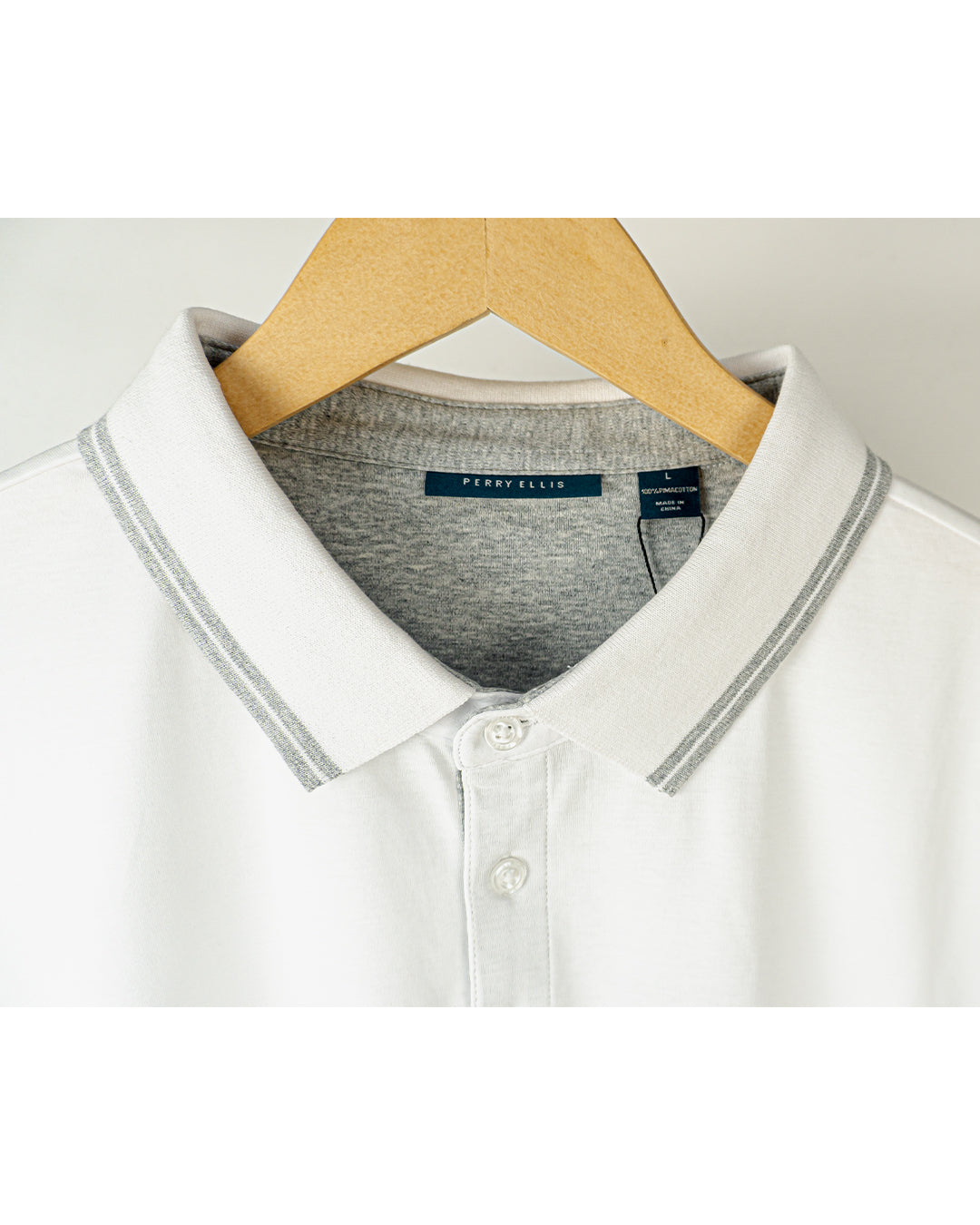 Tipo polo Perry Ellis, blanco con detalle gris en el cuello y mangas.